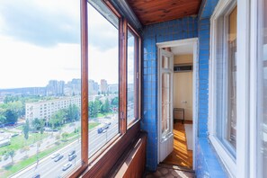 Quarto com uma grande janela com vista para a paisagem urbana, teto de madeira e parede com azulejos azuis.
