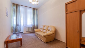 Una habitación con un sofá de cuero color beige, un armario de madera y una mesa con superficie de vidrio.