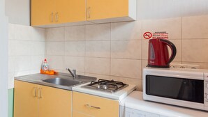 Una cocina con armarios amarillos, estufa a gas, microondas y hervidor.