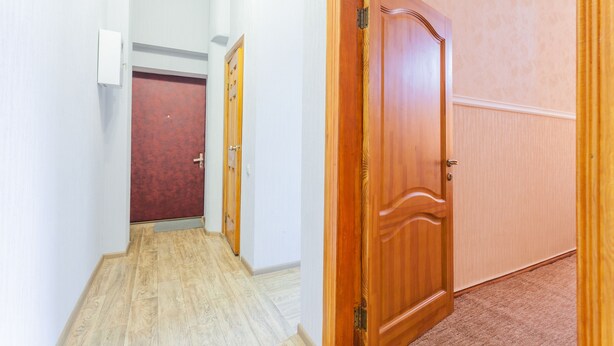 Un pasillo con puertas de madera, una puerta roja y una pared blanca.
