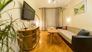 Un salón acogedor con un sofá, una mesa de centro, un televisor montado en la pared y una bicicleta.