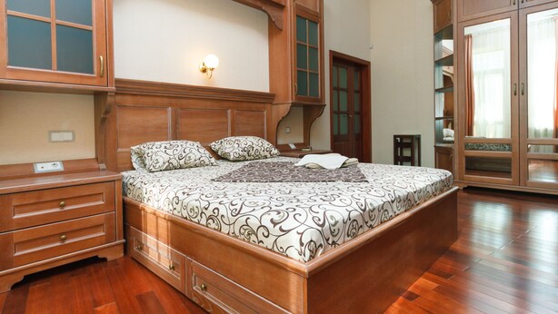 A spacious bedroom with a large bed, wooden wardrobe, and built-in shelves. - Apartment near Olympic Stadium (Kyiv)