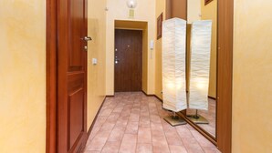 A hallway with a wooden door, a light fixture, and a wall-mounted light. - Apartment near Olympic Stadium (Kyiv)