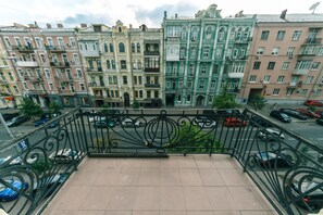 A balcony with a view of multi-story buildings, a street with parked cars, and a clear sky. - 4 bedroom apartment at the Palace of Sport (Kyiv)