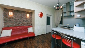 Een kleine keuken met een rode bank, barstoelen en een accentmuur van baksteen.