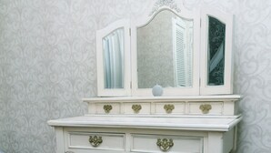 Een witte kaptafel met spiegel, lades en een comfortabele kruk.