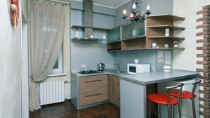 Een kleine keuken met een gasfornuis, magnetron en een bar met krukken.