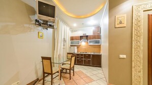 A compact kitchen with a dining area, a TV mounted on the wall, and a decorative door frame.
