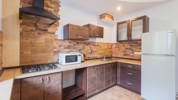 Una cocina con armarios de madera, microondas, estufa y refrigerador.