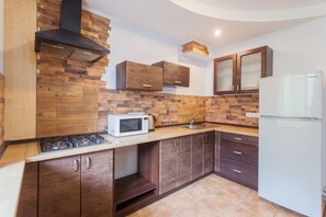 Una cocina con armarios de madera, microondas, estufa y refrigerador.