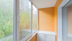 Una habitación con amplios ventanales, paneles de madera y armarios blancos.