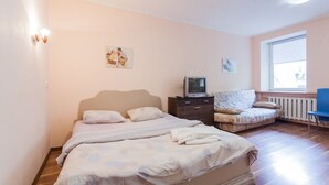 Un dormitorio con cama, televisor, sillón y obras de arte en las paredes.