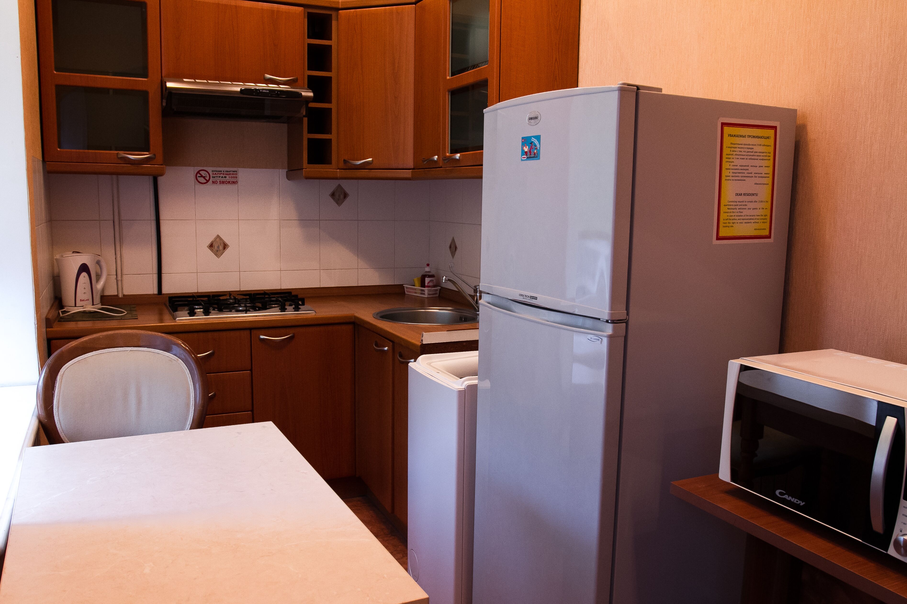 A compact kitchen with wooden cabinets, a stainless steel sink, a microwave, and a refrigerator.