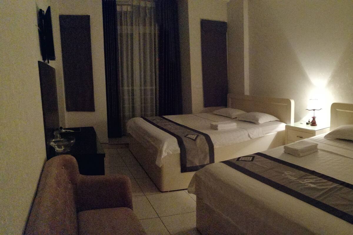 A hotel room with a bed, bedside table, chair, and curtains.