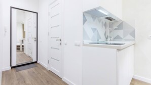Ein modernes, minimalistisches Badezimmer mit einem weißen Waschtisch, einem Spiegel mit geometrischem Muster und einer Duschkabine.