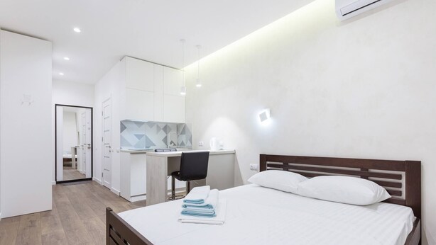 Ein modernes Hotelzimmer mit Bett, Schreibtisch und einer Küchenzeile.