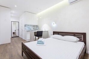Et moderne hotelværelse med seng, skrivebord og tekøkken.