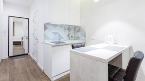 Eine moderne, minimalistische Küchenzeile mit weißer Arbeitsplatte, einer Glasrückwand und einem Wasserkocher auf der Theke.