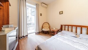 Una habitación de hotel con una cama, una silla, una mesita y una ventana con cortinas.