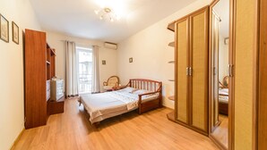 Un dormitorio con cama de madera, un armario, una silla y un escritorio con lámpara.