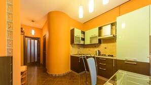 Una cocina moderna con una pared curva, un comedor con mesa de vidrio y una isla de cocina visible.