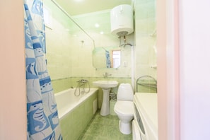 A bathroom with a bathtub, a sink, and a toilet. - Cozy studio apartment near Palace Ukraina (Kyiv)