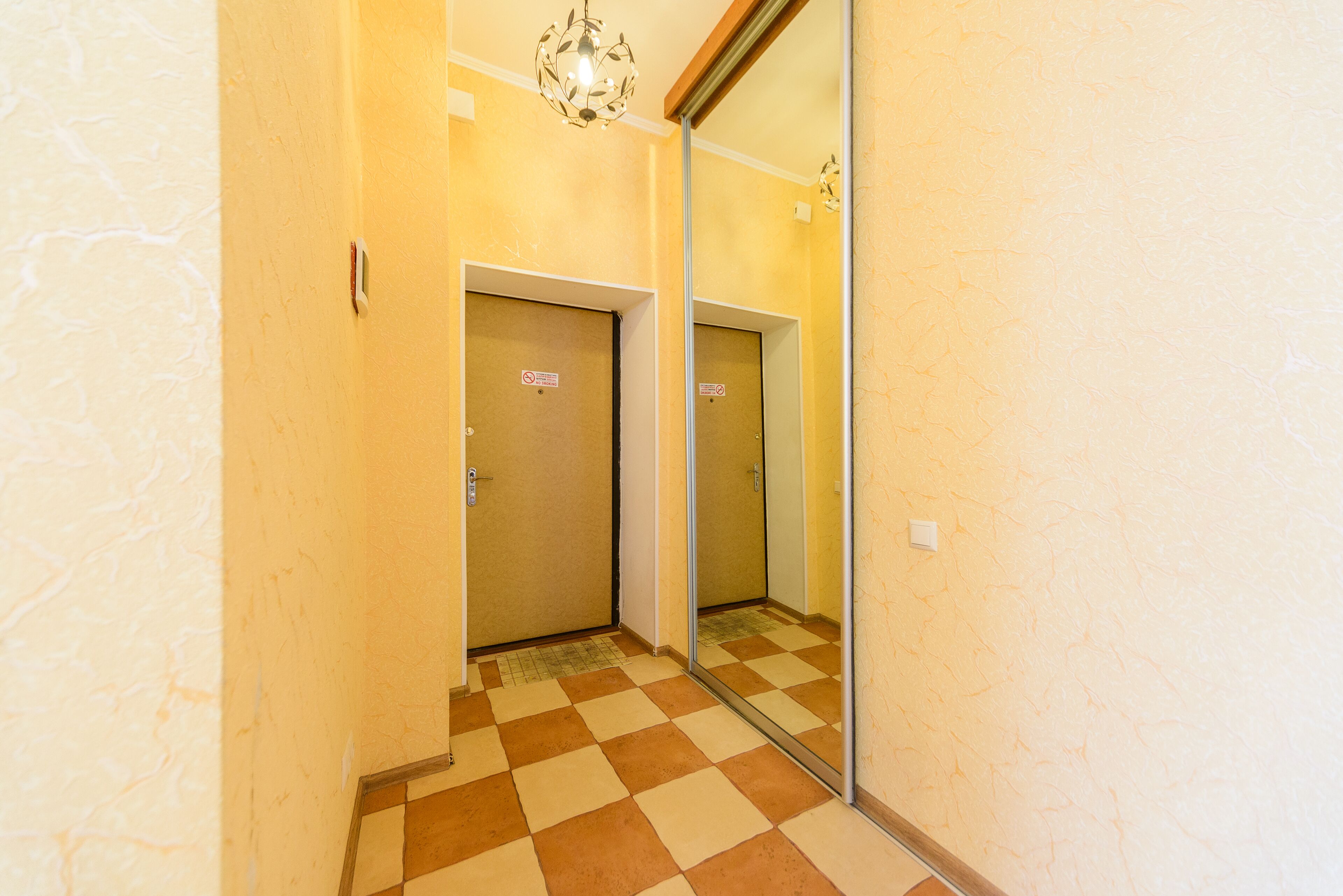Un pasillo con suelo a cuadros, un espejo en la pared y dos puertas con el cartel de 'No Entry'.
