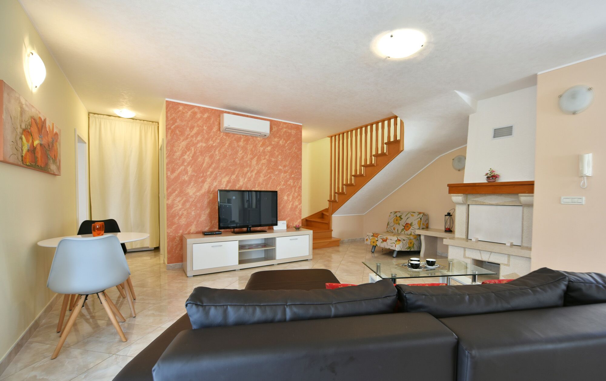 A modern living room with a sofa, a TV, and a staircase leading to another level.