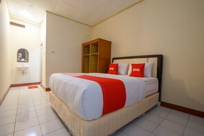 Een hotelkamer met een bed, een houten kledingkast, een wastafel en een spiegel.