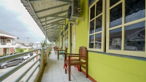 Un balcon fermé, doté de chaises et d’une balustrade, donnant sur une rue.