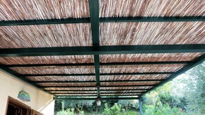 A covered outdoor area with a metal frame and a thatched roof.