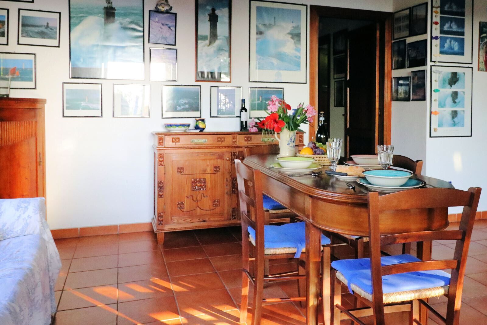 A dining area with a wooden table and chairs, a cabinet, and framed pictures on the wall.