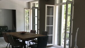 Un comedor con mesa y sillas de madera, ventanas amplias y vistas al exterior.