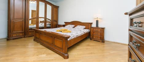 A bedroom with a wooden bed, a nightstand, a dresser, and a wardrobe.