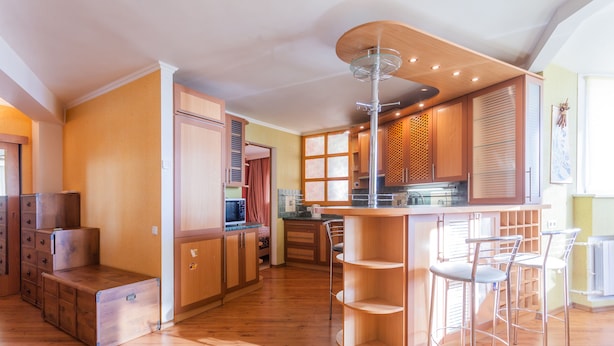 Eine moderne Küche mit Holzsäulen, einer zentralen Kochinsel mit Barhocker und einem eingebauten Backofen.