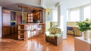 Eine moderne Küche mit Holzschränken, einer Bar und einem Essbereich mit Stuhl und Tisch.