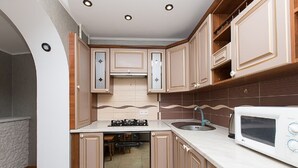 A compact kitchen with wooden cabinets, a built-in oven, a microwave, and a sink. - Apartment on Obolon (Kyiv)