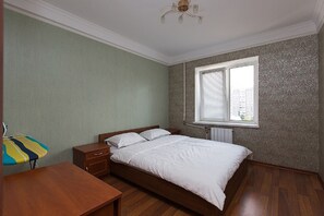 A bedroom with a wooden bed, a nightstand, a dresser, and a window with blinds.