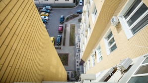Un immeuble de grande hauteur à la façade jaune, doté de nombreuses fenêtres et surmonté d’un parking.