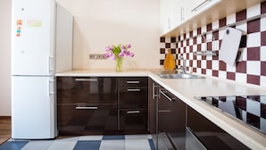 Une cuisine moderne avec un réfrigérateur blanc, des armoires noires, un pare-feu à carreaux et un vase de fleurs posé sur le comptoir.