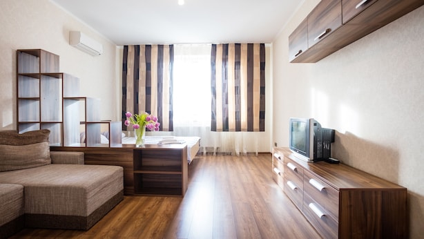 Un salon moderne avec un canapé d’angle, un meuble TV en bois et un coin repas agrémenté de rideaux à rayures.