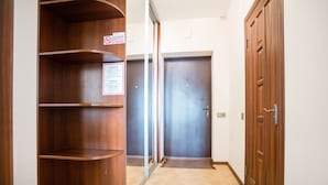 Un couloir avec des étagères en bois, un panneau indiquant qu’il est interdit de fumer et deux portes fermées.