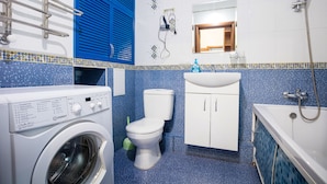 Une salle de bain équipée d’un lave-linge, de toilettes, d’un lavabo et d’une baignoire.