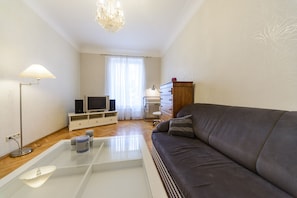 A living room with a sofa, a TV, a lamp, a glass coffee table, and a cabinet. - Apartment near Olympic Stadium (Kyiv)