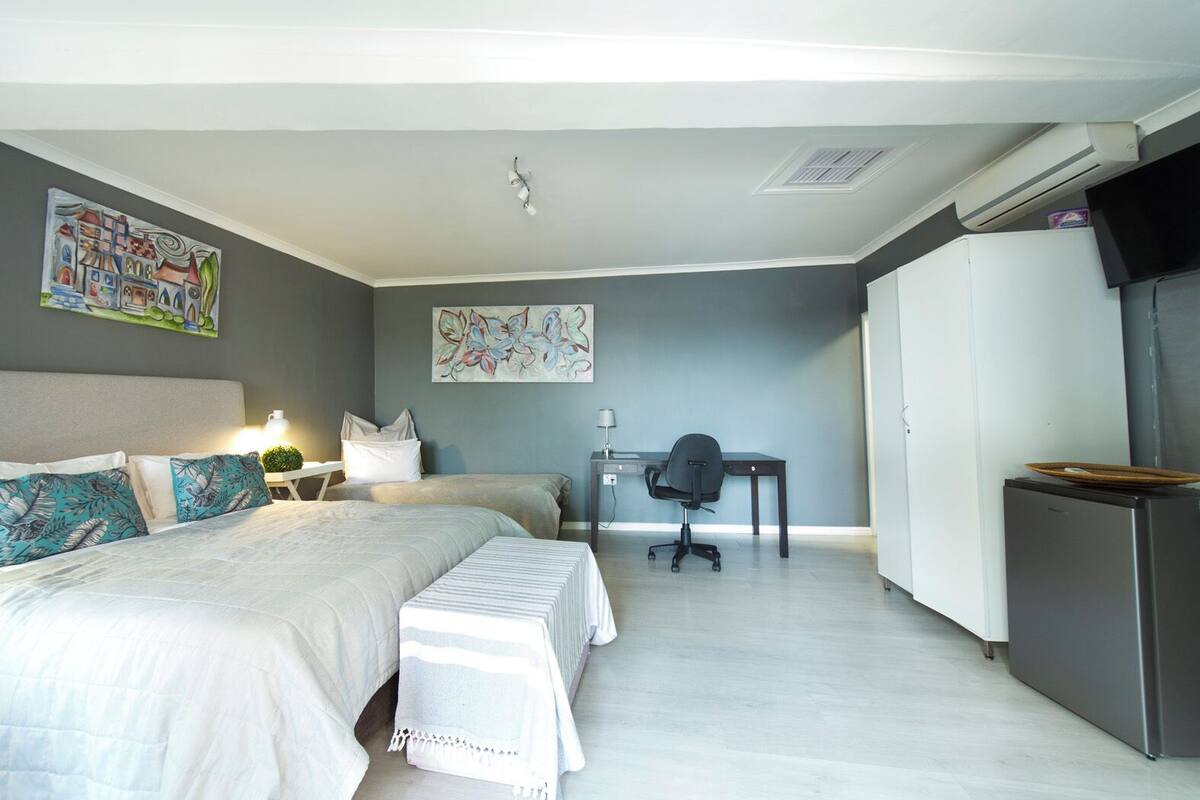 A modern bedroom with a bed, bedside tables, a desk, and a wardrobe.