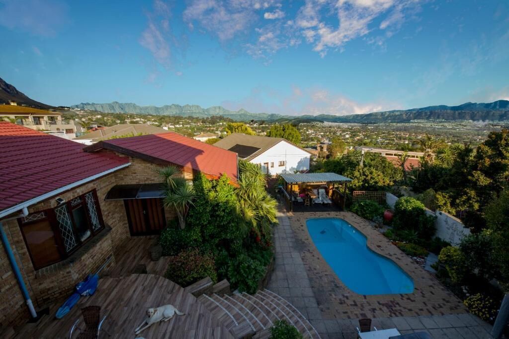 A residential area with a swimming pool, a covered patio, and a view of distant mountains.