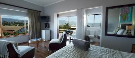 A hotel room with a bed, a sofa, a small table, and a view of the outdoors.