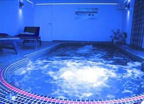 A hot tub with a tiled edge, a lounge chair, and a potted plant. - Bed & Breakfast Crosne Plazza & Spa (Crosne)