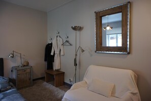 A bedroom with a bed, a bedside table with a lamp, a small wooden stool, a hanging robe, and a mirror on the wall. - Bed & Breakfast Crosne Plazza & Spa (Crosne)