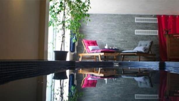 Una habitación con una amplia piscina reflectante, una silla roja, un armario de madera y una planta en maceta.